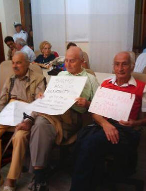 Giulianova, Consiglio Comunale del 3 ottobre 2011 - Tensione alle stelle, poi, per l'episodio che ha visto protagonista Romolo Trifoni (nella foto pubblicata da Pietro Gervasini su facebook). L'ex sindaco di Giulianova ha inscenato una protesta contro la vendita della farmacia, indossando un cartello "Gi le mani dalla farmacia" e rivolgendo anche frasi molto dure verso l'Amministrazione Comunale. Trifoni  stato allontanato dall'aula consiliare dai vigili urbani di servizio dopo avere avvertito anche un malore.